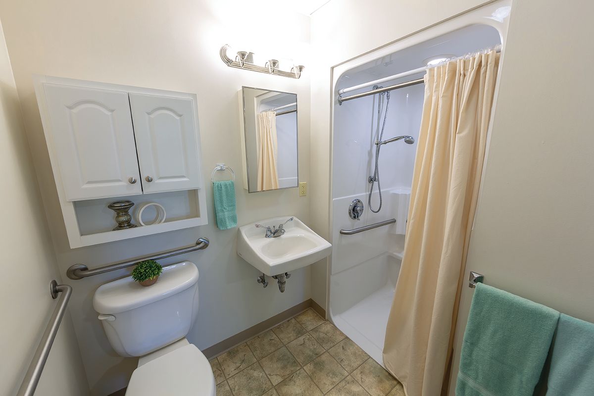 A compact bathroom with a sink, shower, and toilet.