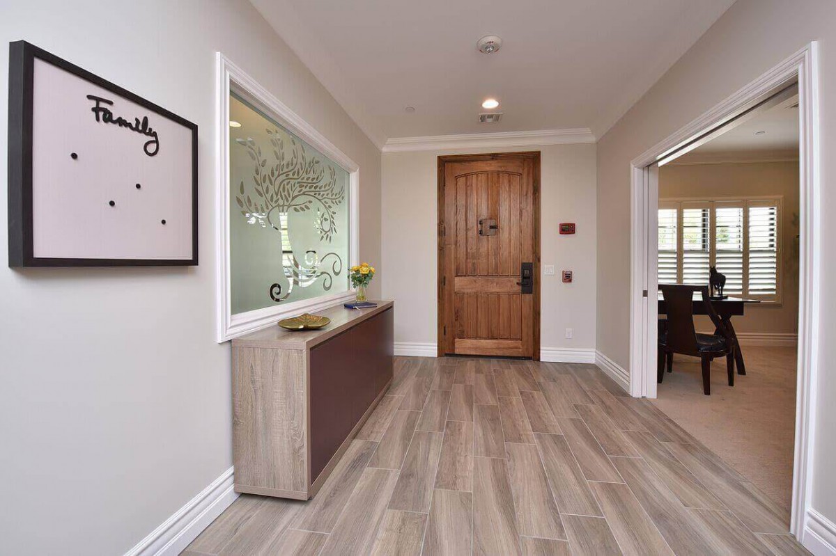 A modern hallway with wooden flooring and minimalistic decor leading to a wooden door.
