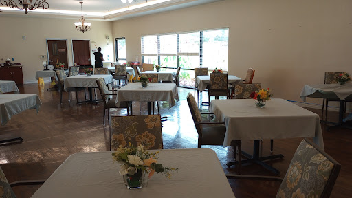 A spacious and well-lit dining area featuring neatly arranged tables and chairs, adorned with floral centerpieces.