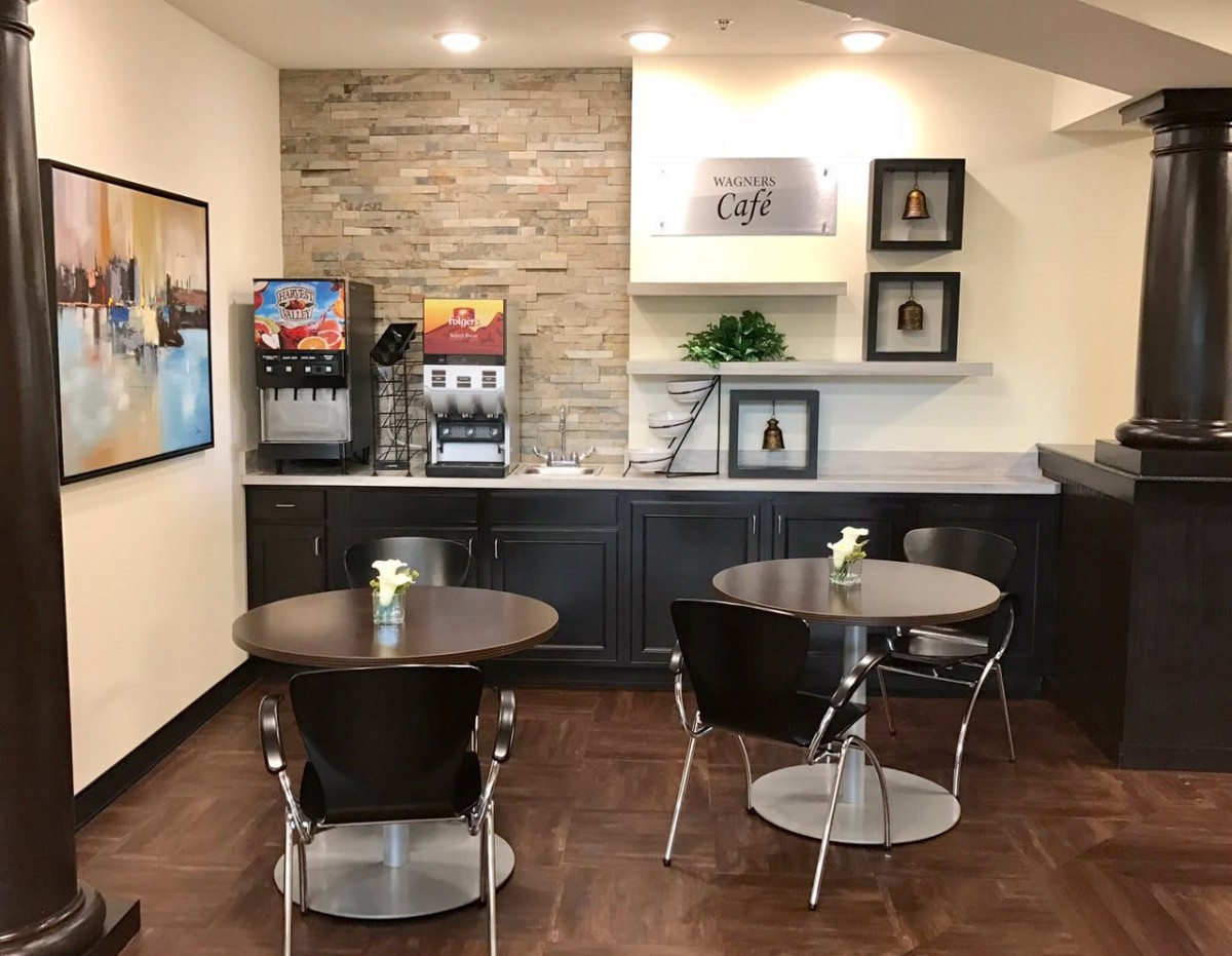 A modern cafe seating area with tables, chairs, and a beverage station.