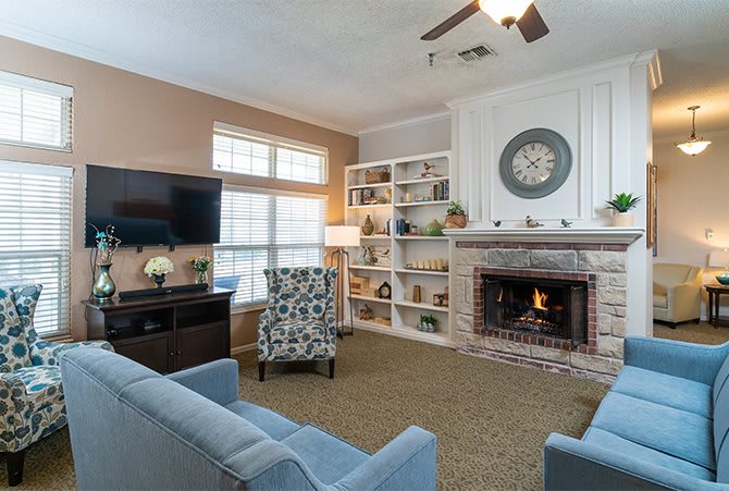 A cozy living room featuring a fireplace, comfortable sofas, and a large TV.