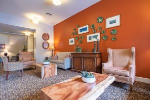 A cozy living room with modern decor featuring an orange accent wall and a collection of artwork.
