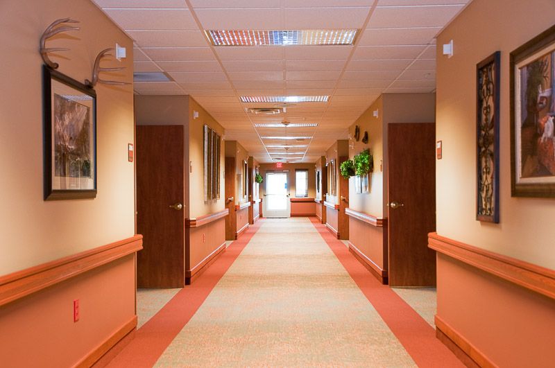 A well-lit, carpeted hallway with multiple doors and artwork on the walls.