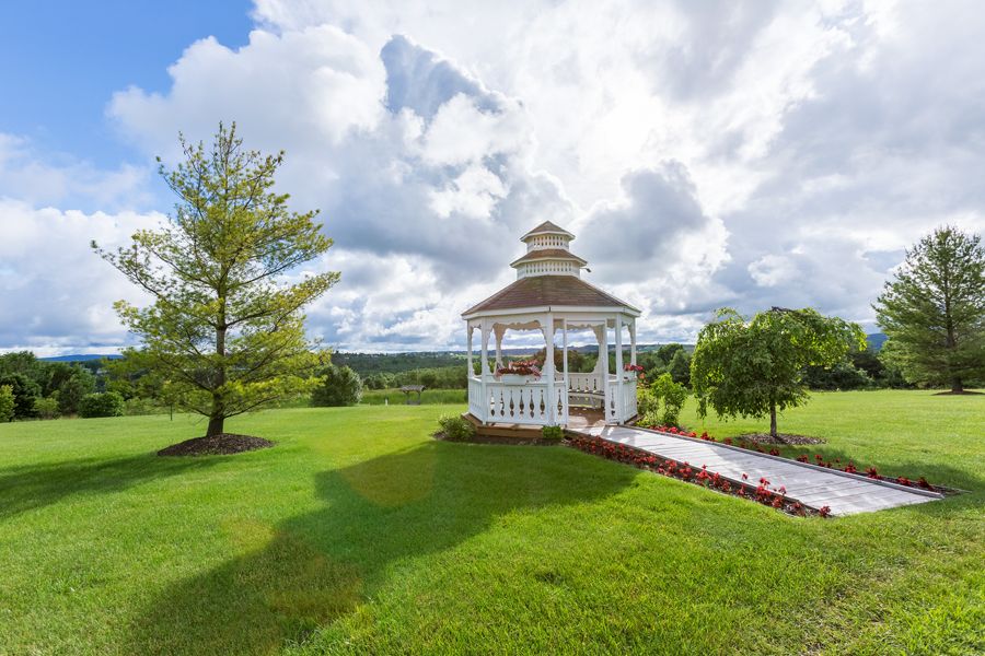 A picturesque gazebo set in a lush, green landscape under a partly cloudy sky.
