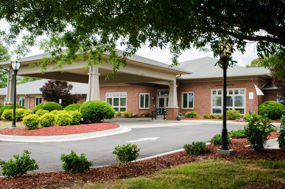 A building entrance surrounded by landscaped greenery and a driveway.