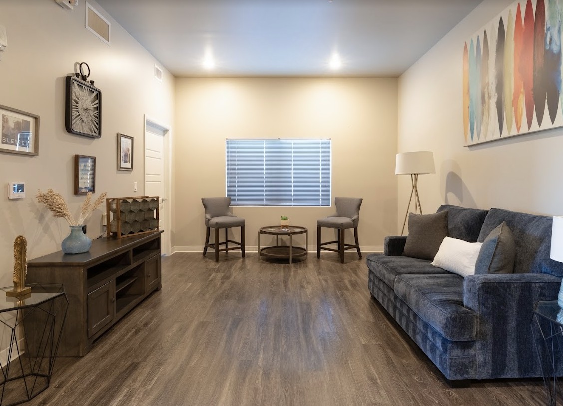 A modern living room with a sofa, chairs, and a wooden floor.