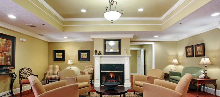 A modern living room featuring a central fireplace, elegant chairs, and a chandelier.