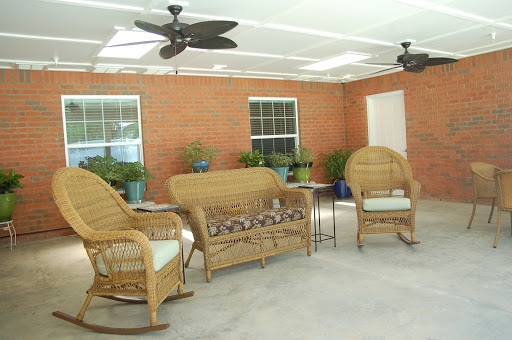 A cozy patio area featuring wicker furniture and ceiling fans, ideal for relaxation.