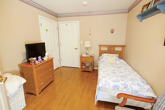 A cozy bedroom with a single bed, wooden furniture, and a television.