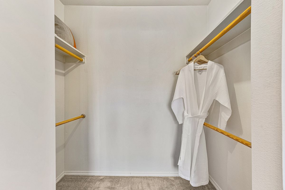 A minimalist walk-in closet with a single robe hanging on a wooden hanger.