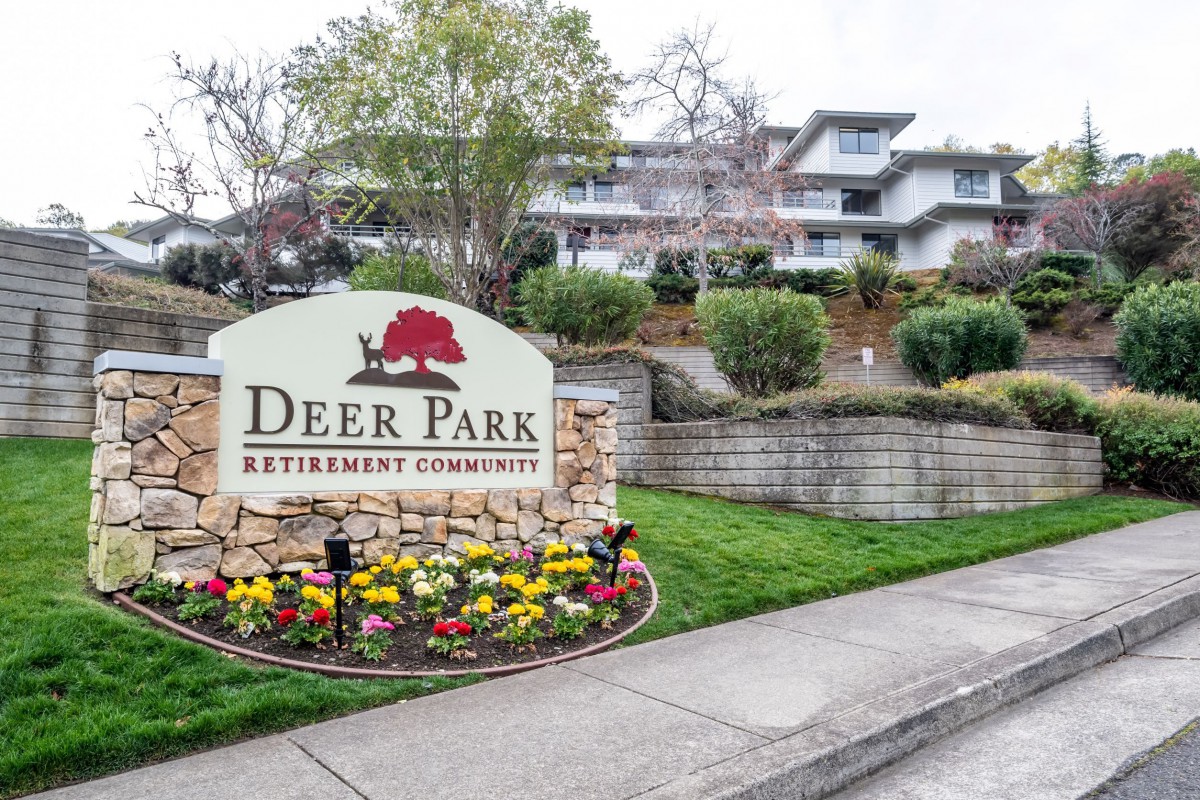 Entrance sign for Deer Park Retirement Community with well-maintained landscaping and building in the background.
