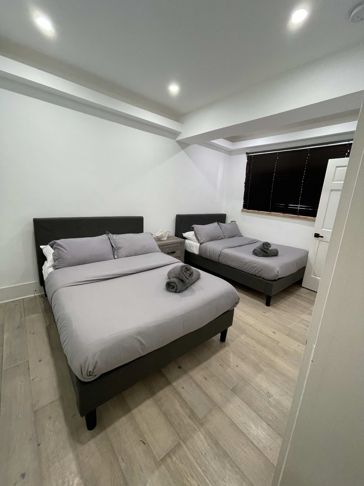 A modern bedroom features two neatly made beds with gray linens and stylish decor.