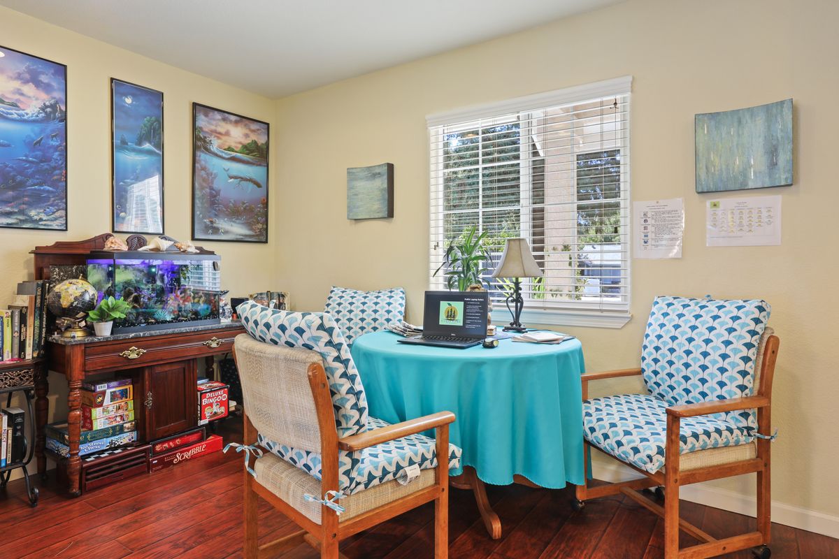 A cozy home office with a round table, patterned chairs, and an aquarium, featuring artwork on the walls.