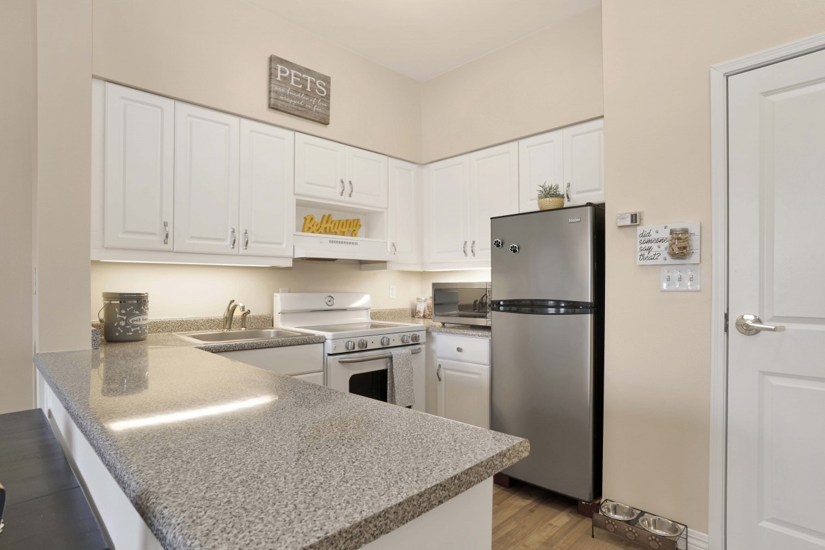A modern kitchen with white cabinets and stainless steel appliances.