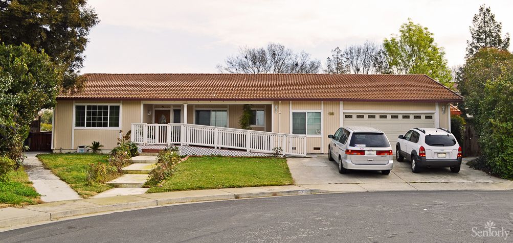 A single-story suburban house with a wheelchair ramp and a van parked in the driveway.
