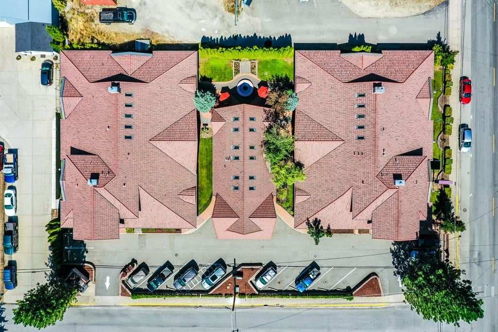 Aerial view of a suburban apartment complex with neatly arranged buildings and a landscaped courtyard.
