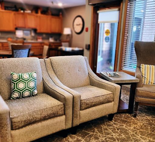 A cozy living room setup featuring stylish chairs and a modern kitchen in the background.