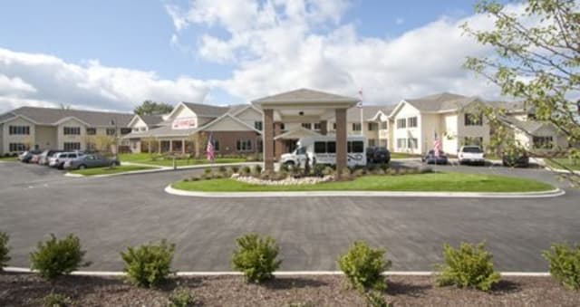 A large building with a covered entrance and circular driveway under a cloudy sky.