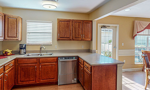 A bright kitchen with wooden cabinets and a modern countertop featuring a sink and dishwasher.