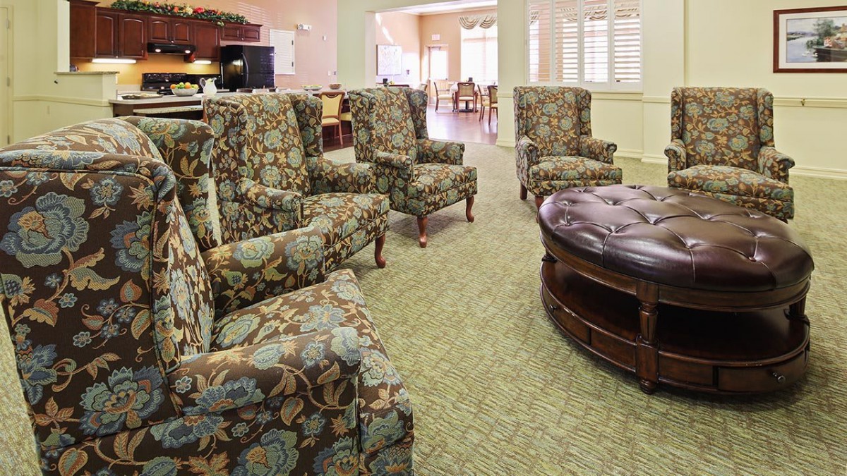 A cozy seating area with floral upholstered chairs and a round leather ottoman.