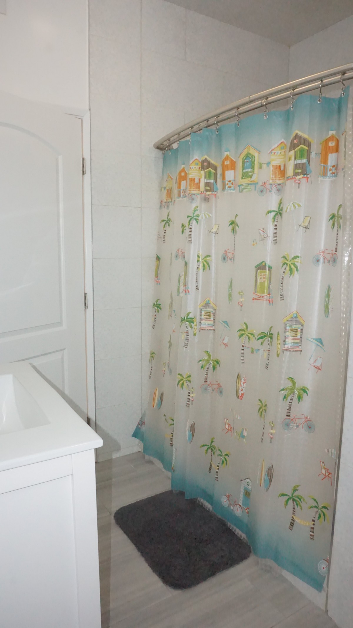 A bathroom with a tropical-themed shower curtain and a sink.