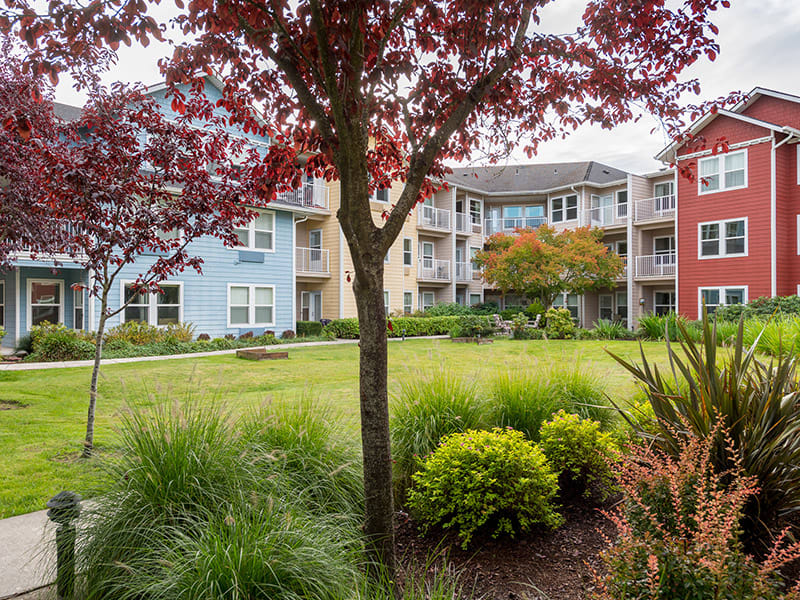A scenic view of a residential apartment complex with landscaped gardens and vibrant trees.