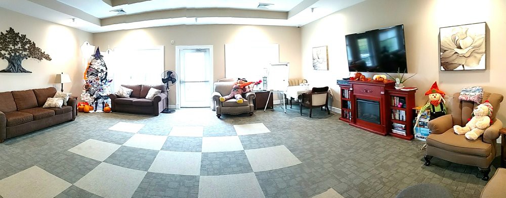 A bright living room with modern furniture, including sofas, chairs, and a television.