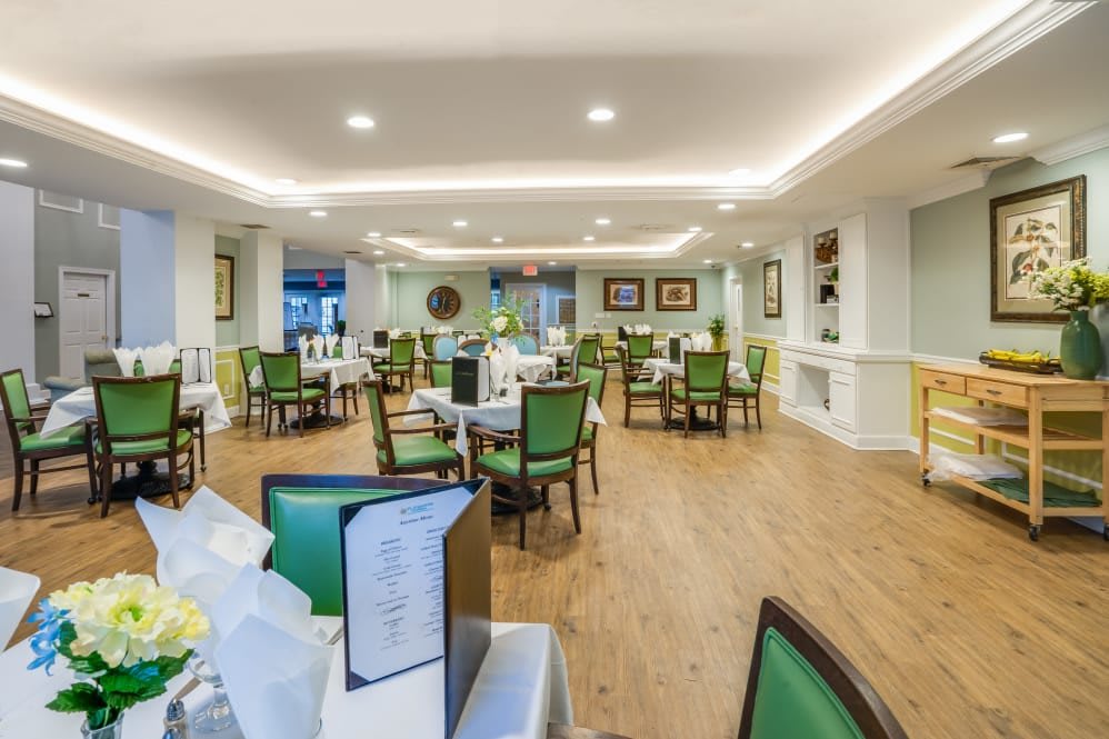 A modern and well-lit dining room with green chairs and neatly arranged tables.