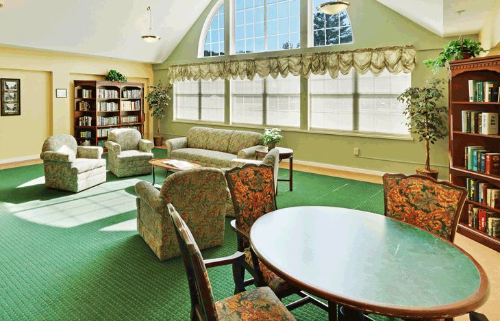 A cozy living room with comfortable seating, large windows, and a bookshelf.