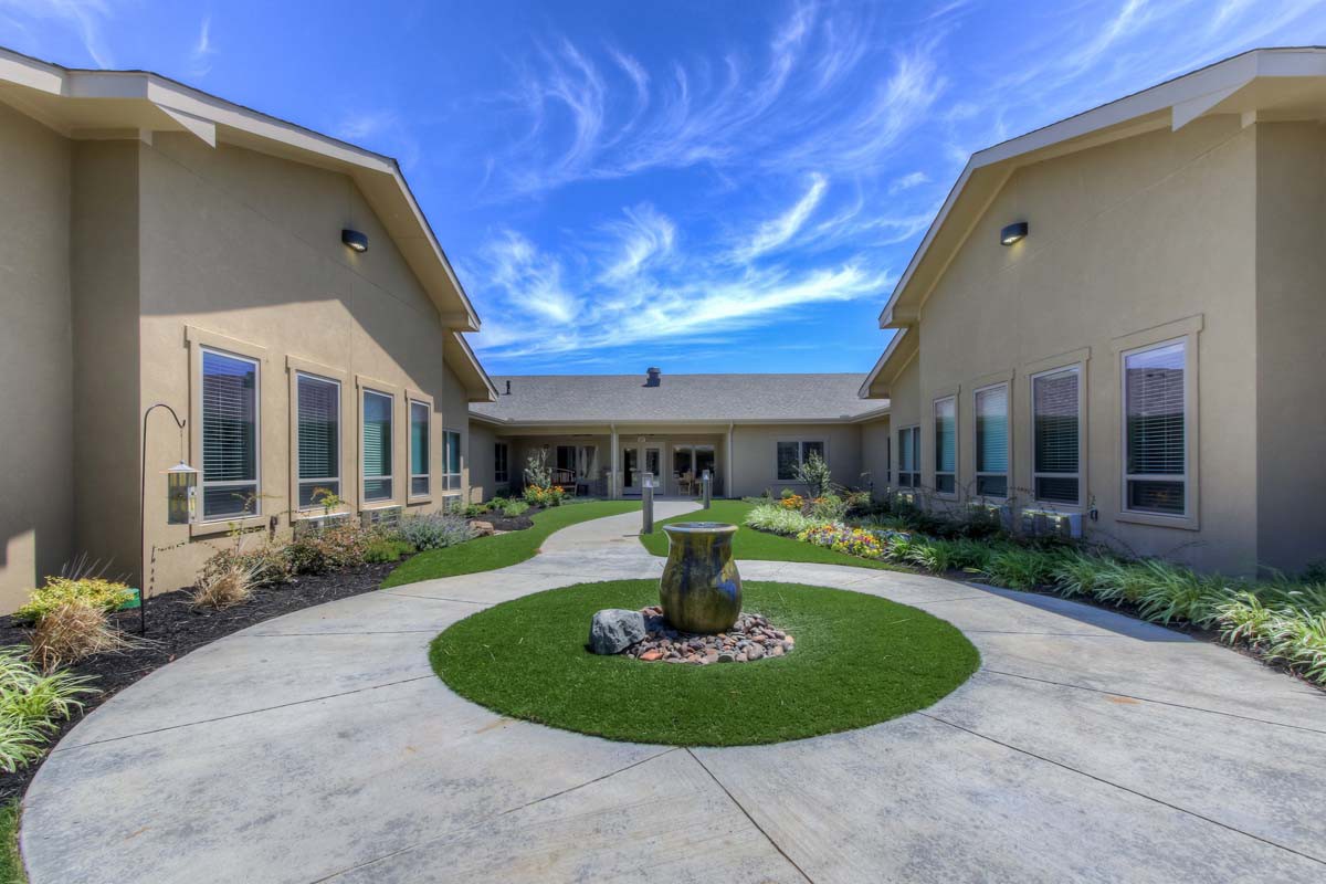 A modern courtyard with landscaped gardens and a clear blue sky.