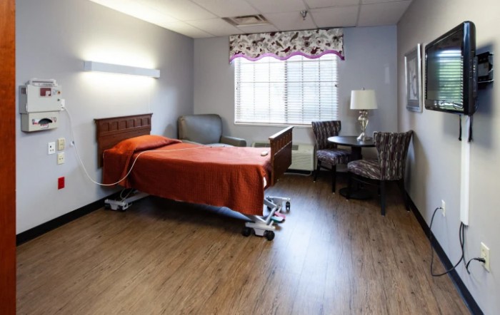 A hospital room with a single patient bed and seating area.