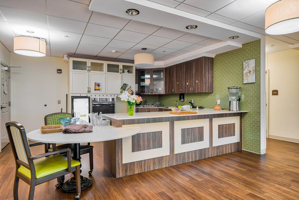 A modern kitchen interior featuring a sleek design with wood flooring, green walls, and a spacious countertop.