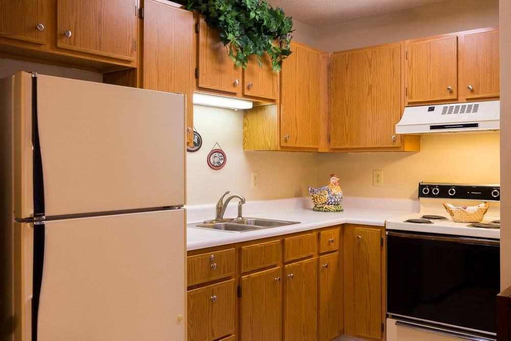 A cozy kitchen with wooden cabinets, a refrigerator, and modern appliances.