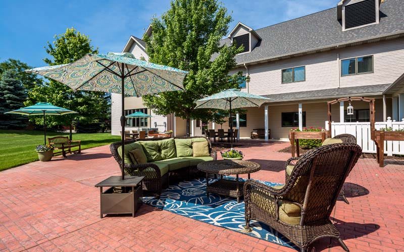 A cozy outdoor seating area with umbrellas on a patio adjacent to a building.