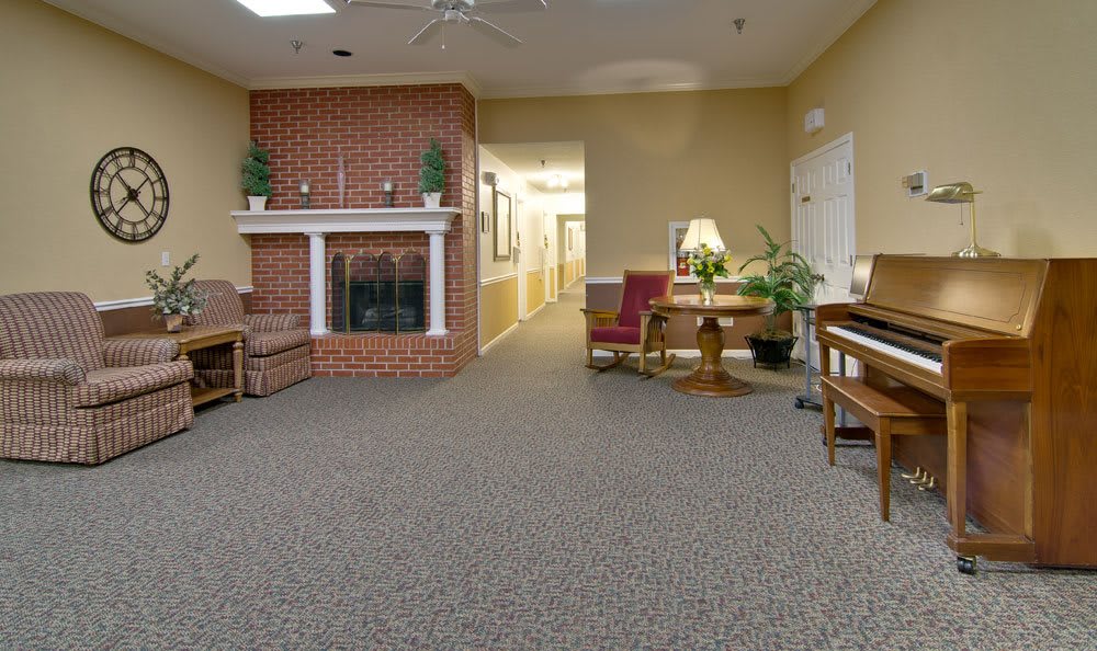A cozy living room with a brick fireplace, seating area, and decorative plants.