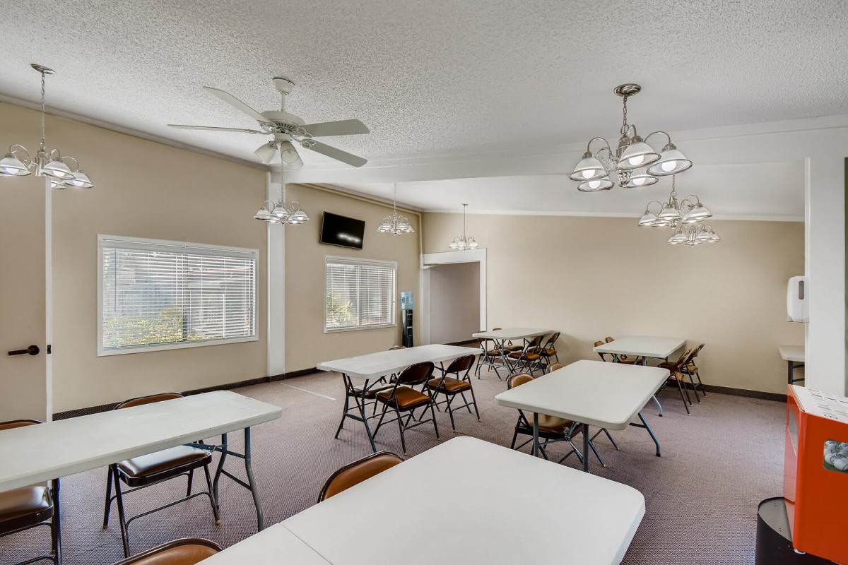 An interior view of a meeting room with tables and chairs, featuring ceiling fans and chandeliers.