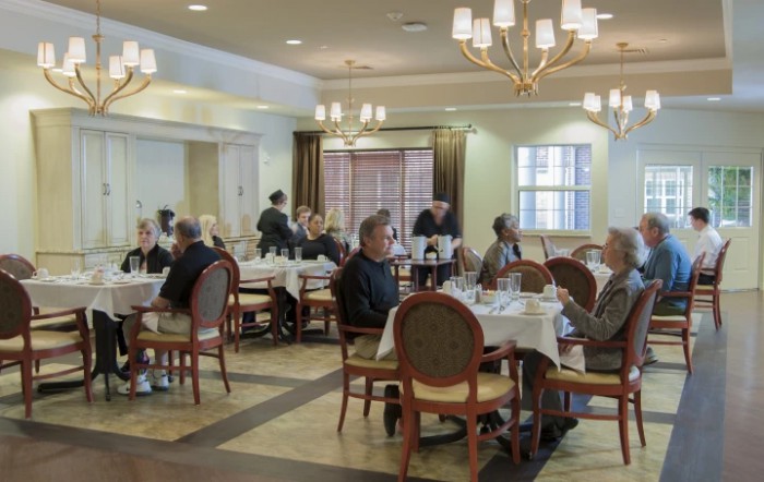 A dining room with patrons seated at tables, enjoying their meals in a warmly lit restaurant setting.