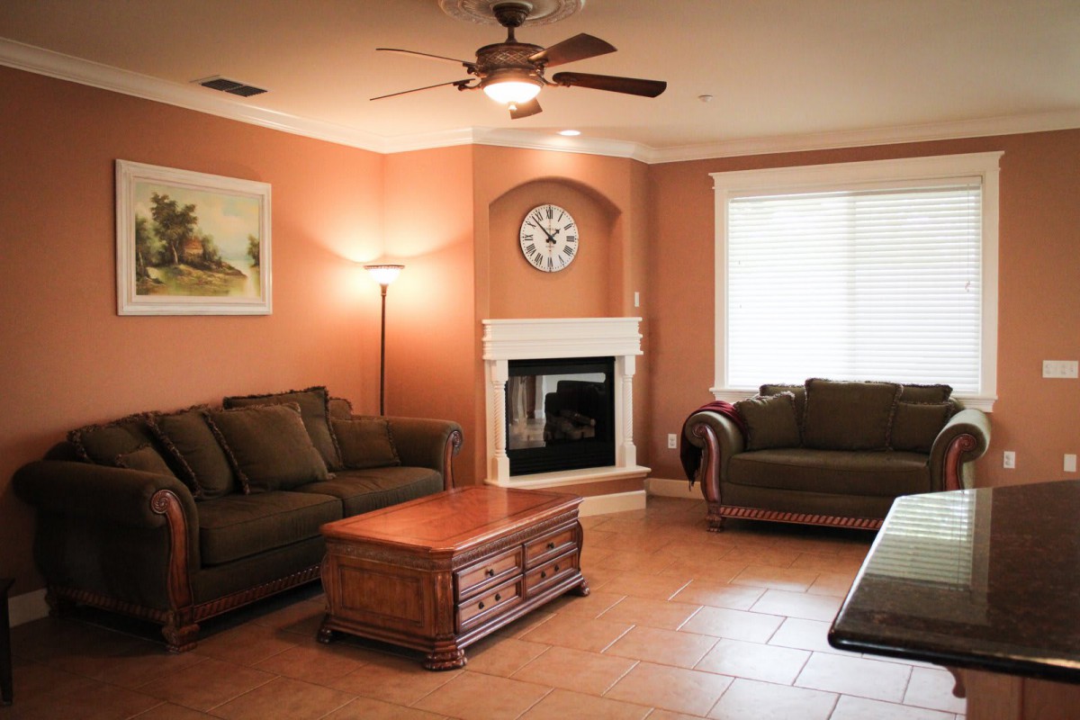 A cozy living room with comfortable sofas, a wooden coffee table, and a fireplace under a clock.