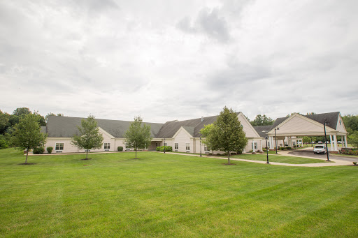 A view of a suburban residential area featuring well-maintained buildings and lush green lawns under a cloudy sky.