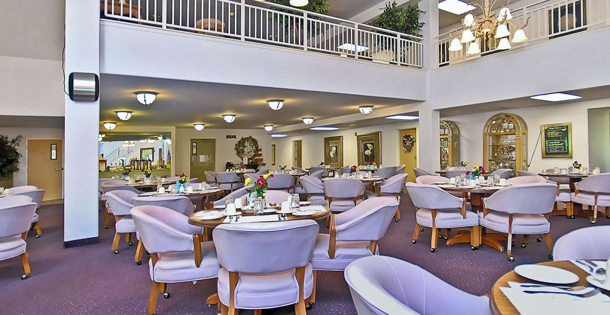 A spacious and elegantly designed dining area with multiple tables and chairs, featuring soft lighting and tasteful decor.