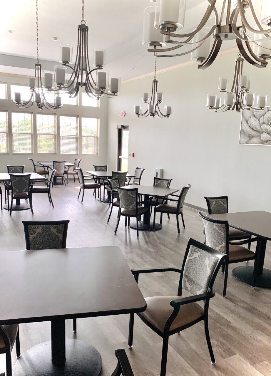 A modern, empty dining room with multiple tables and chandeliers.