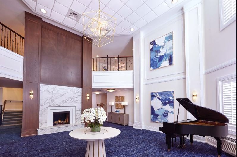 A luxurious lobby featuring a grand piano, chandelier, and modern artwork.