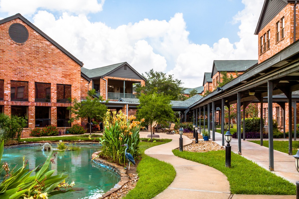 Beautiful outdoor scene with modern buildings, a scenic pond, and lush greenery.