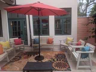 A cozy outdoor patio with colorful cushions and a red umbrella.