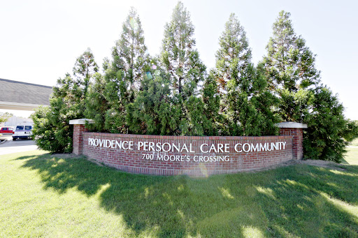 Welcome sign for the Providence Personal Care Community, surrounded by trees.