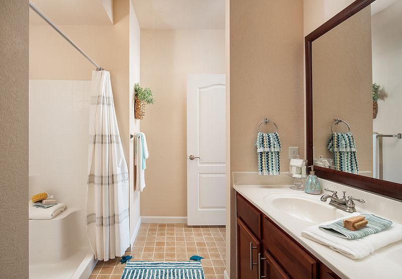 A clean and tidy bathroom with a double sink vanity, striped shower curtain, and tile flooring.