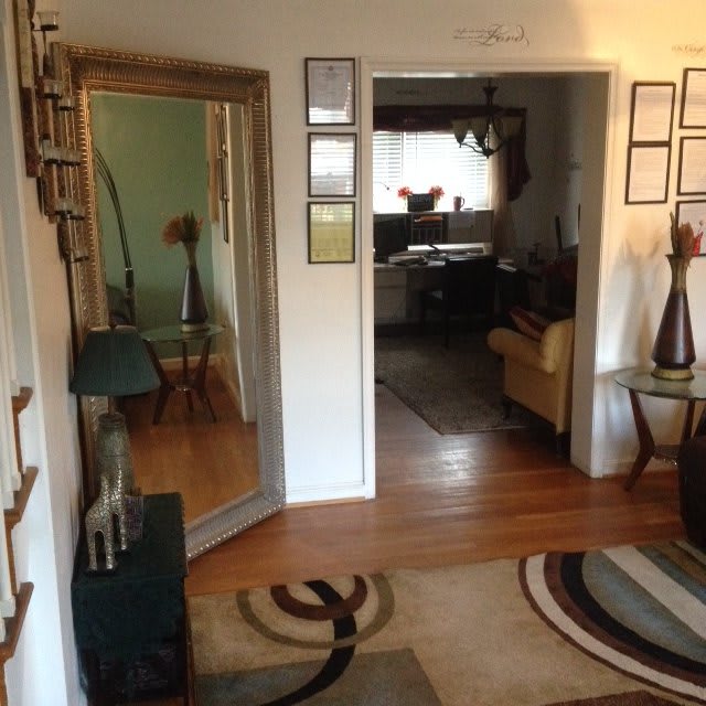 A modern living room with a large mirror, decorative elements, and wooden flooring.