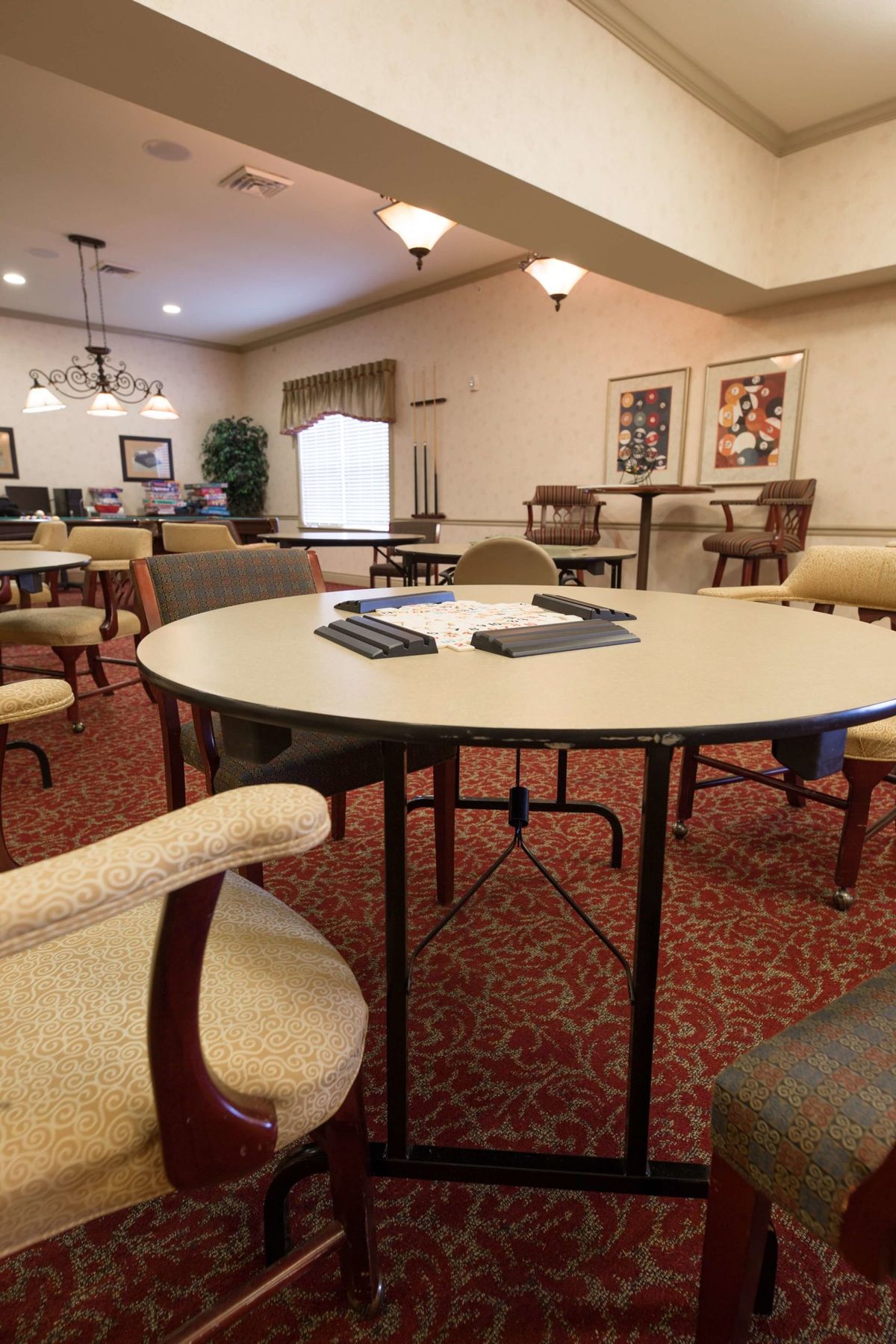 A well-lit meeting room with several tables and chairs arranged neatly on a patterned carpet.