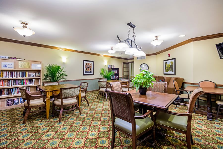 A well-decorated dining room with a large table, elegant chairs, and indoor plants.