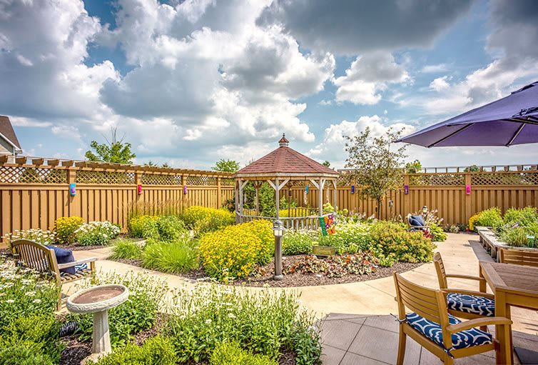 A beautifully landscaped garden with a gazebo and vibrant flowers under a partly cloudy sky.